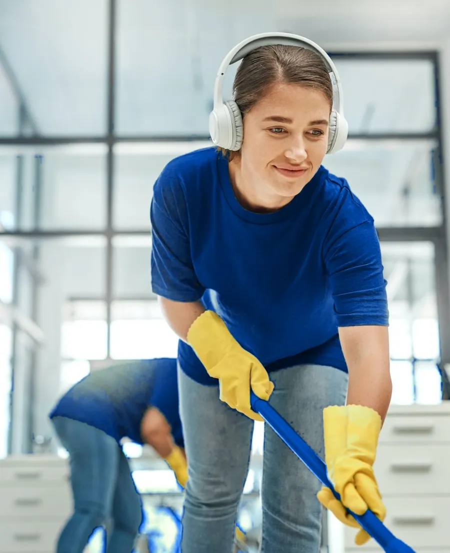 Professional cleaner in blue cleaning an office